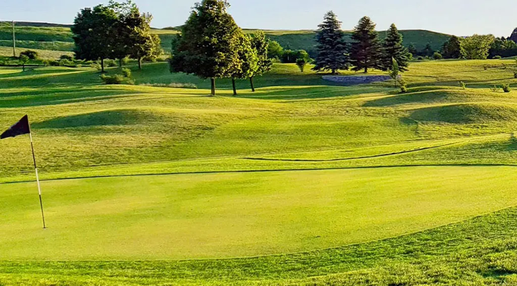 A golf course featuring terrain variations, landscaping and smooth greens.