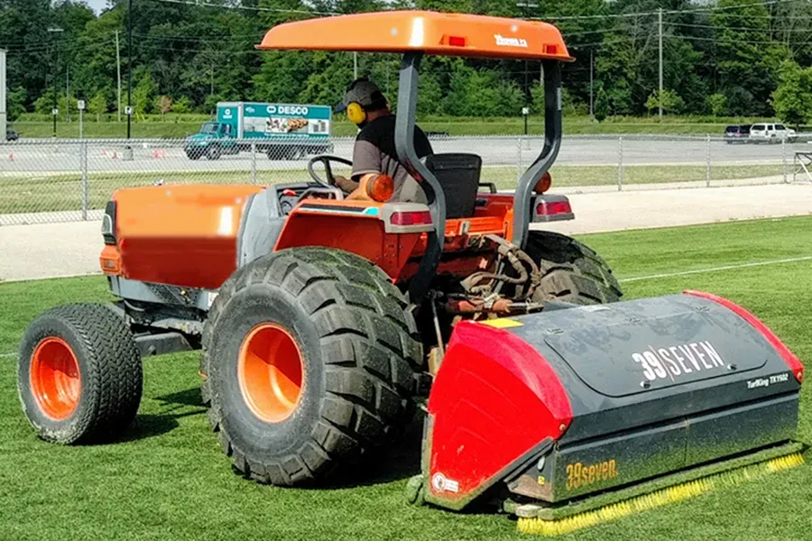 A tractor with a turf maintenance implement attached.