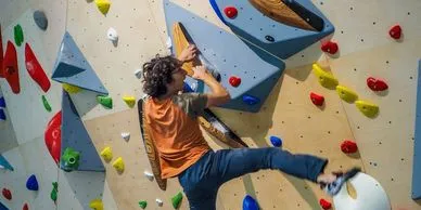 A young man climbs an indoor climbing wall.