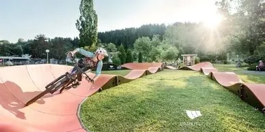 A bicycle rider zooms around a wavy pump track.