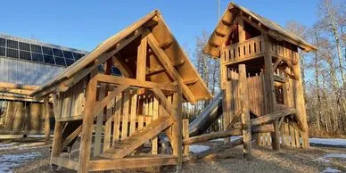 A wood playground structure featuring two towers.