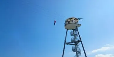 A zipliner takes off from a zipline launch tower.