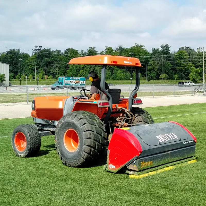 A tractor tows an artificial turf maintenance implement.